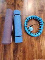 Two rolled mats and weighted hula hoop laid out on floor