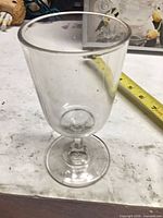 Full view of clear stemmed goblet beside tape for scale