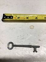 Skeleton key beside tape measure showing length under 5 inches