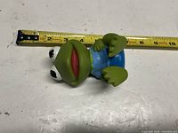 Side view showing full Baby Kermit figure with tape for scale