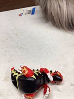 Figure left side showing black body with yellow markings and red limbs