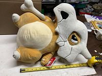 Cubone plush on its back beside tape measure showing length