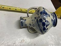 Side view showing floral decoration, twin handles, tape measure for scale