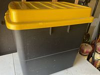 Overall view of black storage bin with yellow lid