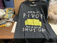 Front view of black Friends "Pivot" size large T-shirt with graphic text and couch illustration