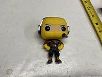 Front view of loose Funko Pop! Raptor figure with ruler showing ~4 inch height