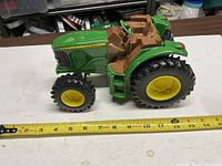 Side view of the John Deere toy tractor with tape for scale