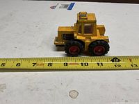 Left side view of yellow Lesney tractor beside ruler showing length