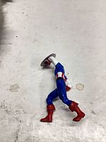 Full figure left side view lying on surface, shows shield and costume details