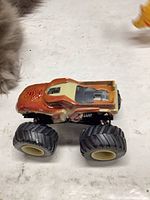 Side view of orange/cream monster truck showing body graphics and tire detail
