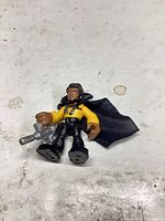Figure lying on surface showing front details, cape and blaster visible