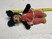 Full view of Minnie Mouse plush doll next to tape measure showing length
