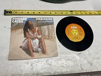 Front of picture sleeve and record label visible with measuring tape for scale