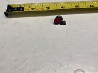 Front view of the Quebec Nordiques enamel pin beside measuring tape showing size
