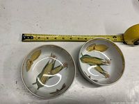 Top view showing both bowls and tape measure indicating approx 5 in diameter, interior motifs visible