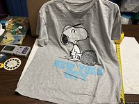 Front view of grey Snoopy New York City T-shirt showing graphic and size reference tape