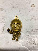 Front view of gold C-3PO keychain charm showing painted details and hanging loop