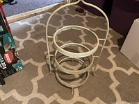 Full view of white metal three-tier stand showing rings, handle and feet