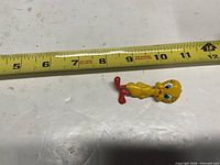 Front view of Tweety Bird brooch beside tape measure