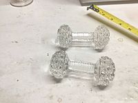 Two clear crystal knife rests with measuring tape for scale