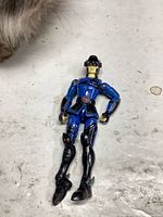 Front view of blue and black articulated action figure showing chest emblem and limb articulation