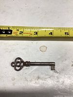 Top view of the iron skeleton key against measuring tape showing length