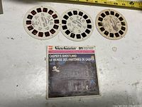 Three View-Master reels and paper sleeve shown on tabletop