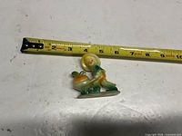 Front view of plastic boy figurine beside tape measure
