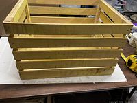 Side view of yellow wooden slat crate showing overall structure and color
