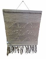 Front of woven tapestry with chevron tufted pattern, fringe and hanging cord