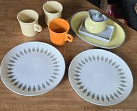 Group view of two patterned dinner plates, three Fiesta mugs, Harkerware platter, tray and sugar bowl