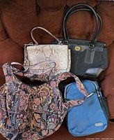 All four handbags arranged on chair for overview