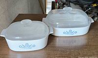 two CorningWare Blue Cornflower casseroles with lids on wooden surface