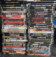 Two tall stacks of WWE DVDs showing spines with various event and documentary titles