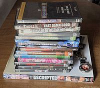 Stack of ten wrestling DVDs on top of book with keychain alongside