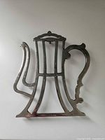 Front view of silver zinc trivet in teapot shape