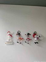 Four Bonhomme ornaments lined up on white surface