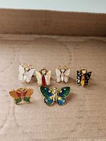 Front view of all six butterfly pins laid out on cardboard