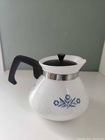 Left side view showing blue cornflower motif, handle, lid, stainless collar