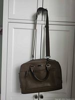 Full view of laptop bag hanging to show overall design, handles and shoulder strap