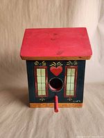 Front view showing entry hole, perch, painted windows and heart, red roof