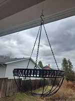 Full view of hanging metal basket with chains and hook attached under roof.