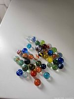 Group of approximately 40 assorted glass marbles on white surface