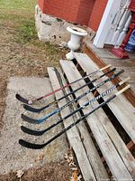 Five hockey sticks side-by-side on steps, full length view