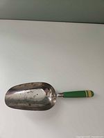Full view of metal scoop with green handle