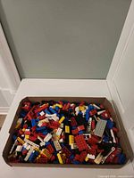 Overview of cardboard box filled with assorted Lego bricks