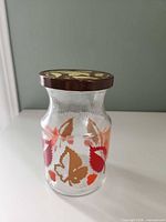 Front view of glass jar showing leaf pattern and brown lid