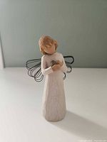 Front view of figurine showing bird, gown texture, wire wings