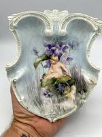 Front view of porcelain plaque showing cherub and floral painting