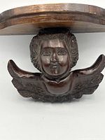 Front view showing carved cherub and underside of shelf